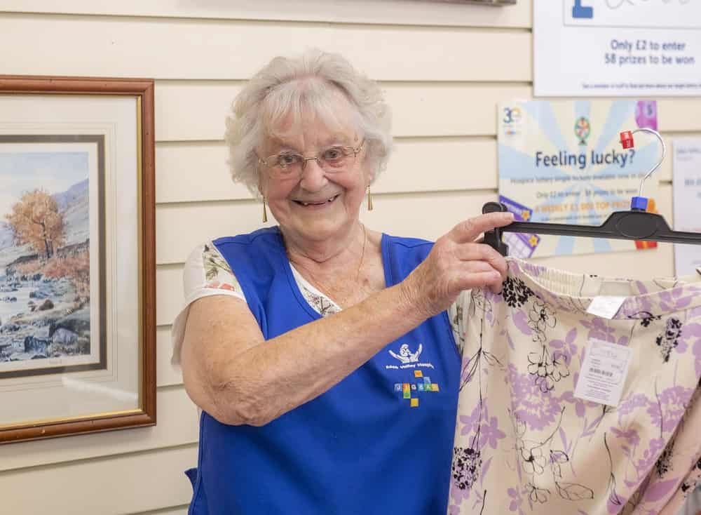 Volunteer holding up item in shop.