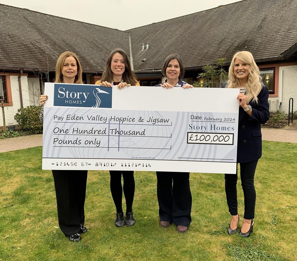 Story Homes donation. Story staff present hospice staff with cheque in walled garden